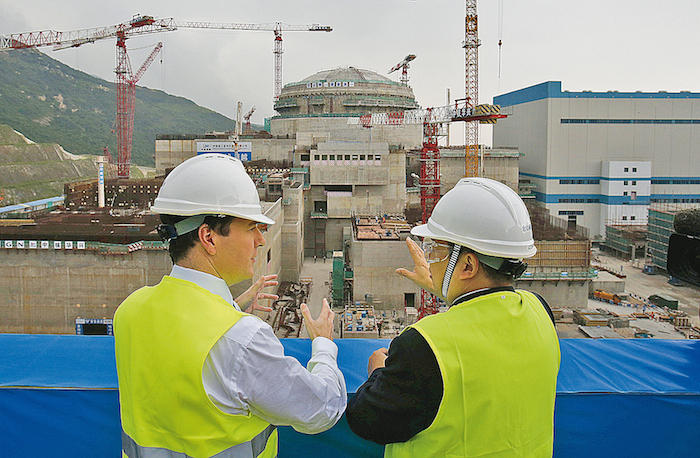 George Osborne (G), chancelier de l’Échiquier britannique, discute avec Guo Liming, directeur général de Taishan Nuclear Power Joint Venture, sur le chantier de construction d’un réacteur nucléaire à Taishan, province du Guangdong, le 17 octobre 2013. Le régime chinois espère remporter plusieurs contrats de construction de centrales nucléaires hors de ses frontières. (Bobby Yip/AFP/Getty Images)