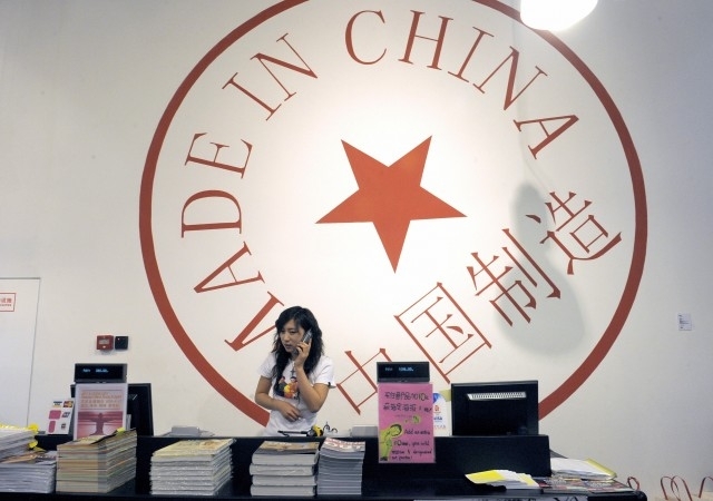 18 juin 2009: une femme est au téléphone derrière le comptoir d’un magasin à Pékin. Derrière elle est affiché un logo «made in China» (fabriqué en Chine). La classe moyenne chinoise évite les produits fabriqués en Chine et préfère consommer les nombreuses marchandises étrangères qu’elle ramène de ses voyages. (Liu Jin/AFP/Getty Images)