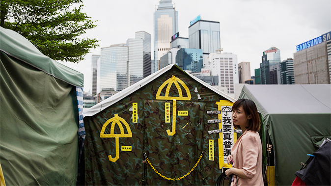 13 juin 2015 : Une femme se tient debout devant des parapluies jaunes, un symbole du mouvement pro-démocrate collé sur une tente à proximité des quartiers généraux de Hong Kong. (Dale de la Rey/AFP/Getty Images)