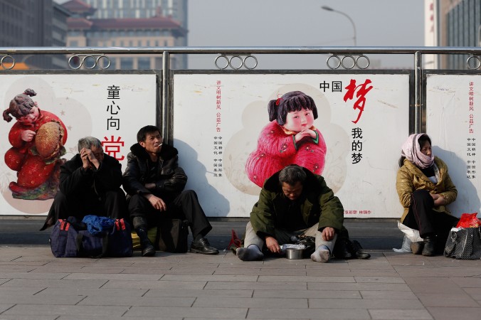 2 mars 2004 : un mendiant est assis devant des affiches propagandistes du régime à la gare ferroviaire de Pékin. Les économies développées reposent sr une classe moyenne élargie – ce que la Chine n’a pas réussi à créer. (Lintao Zhang/Getty Images)   