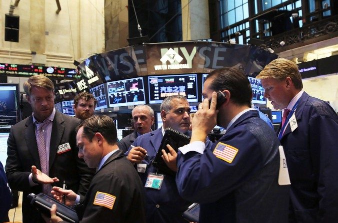 Des traders de la Bourse de New York (NYSE), après que les transactions aient été suspendues pendant prés de quatre heures pour cause de « panne technique », le 8 juillet à New York. Un membre important du collectif des pirates Anonymous, affirme que le régime chinois se trouverait derrière la panne. (Spencer Platt/Getty Images) 