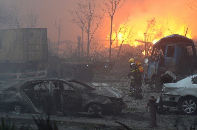 Un pompier passe devant des véhicules endommagés après la série d'explosions dans un entrepôt portuaire de la ville de Tianjin, le 13 août 2015. (STR/AFP/Getty Images)