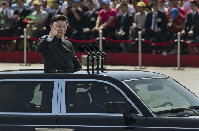 Le dirigeant du Parti communiste chinois Xi Jinping défile dans une voiture à toit ouvert en saluant les soldats sur la place Tiananmen en face la Cité Interdite, lors d'un défilé militaire à Pékin le 3 septembre 2015. Les observateurs ont été surpris lorsque l'ancien chef du régime Jiang Zemin s'est montré à la tribune à côté de Xi Jinping (Kevin Frayer / Getty Images)