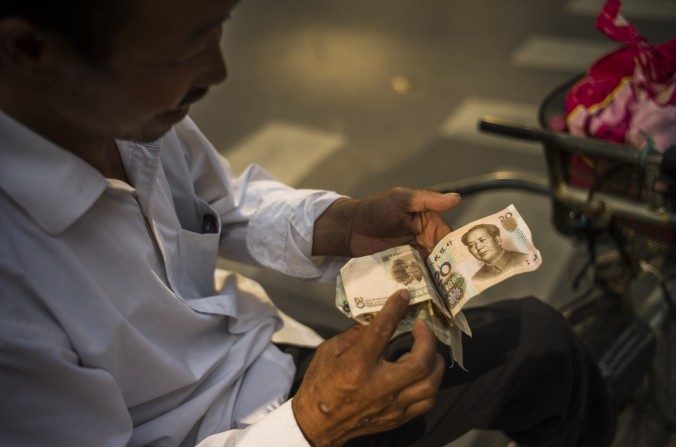 Un homme vérifie une liasse de billet, le 28 juillet 2015, à Pékin. (Fred Dufour/AFP/Getty Images)