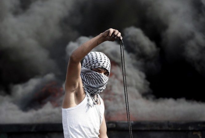 Un manifestant palestinien se prépare à lancer une pierre avec une fronde lors d'affrontements avec les forces de sécurité israéliennes dans la ville cisjordanienne d'Al-Bireh au nord de Ramallah, le 20 octobre 2015. (THOMAS COEX / AFP / Getty Images)