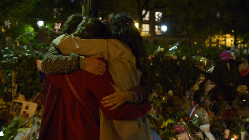 Des gens s'enlaçent devant le mémorial rendu aux victimes du Bataclan. ( BERTRAND GUAY/AFP/Getty Images)