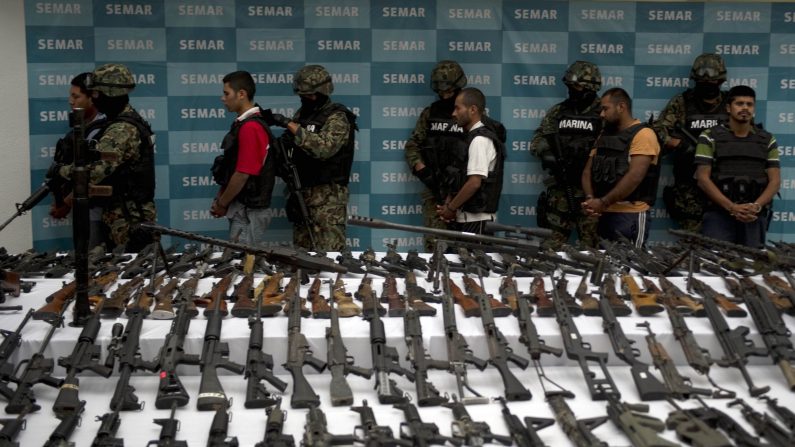 Des marines mexicains escortent 5 trafiquants de drogue présumés, appartenant au cartel Zetas. Devant eux, des grenades, des armes à feux, de la cocaïne et des uniformes militaires destinés aux membres du cartel, le 9 juin 2011 à Mexico. (YURI CORTEZ/AFP/Getty Images)