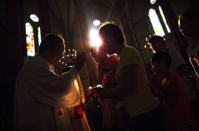 Une Chinoise catholique reçoit la communion d'un prêtre lors d'une cérémonie de la fête de l'Assomption de la Vierge Marie dans une église approuvée par le régime chinois, le 15 août 2014 à Pékin. (Kevin Frayer / Getty Images)
