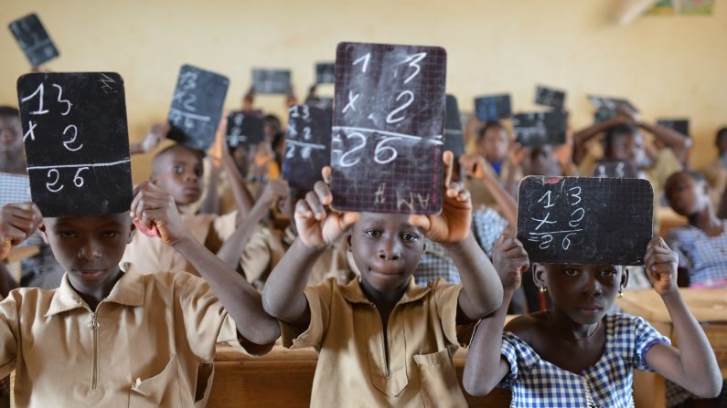 Des enfants d'une classe élémentaire construite en 2013 par le groupe Nestlé, près du village de Goboue, en Côte d'Ivoire. "À cinq ans, j'allais travailler aux champs avec mon père. Aujourd'hui, mes enfants vont à l'école", dit Pierre, un fermier de Bonikro, au centre du pays. Pierre fait partie d'une génération de fermiers qui espèrent pouvoir tenir hors des vastes champs et plantations les enfants de ce pays. (ISSOUF SANOGO/AFP/Getty Images)