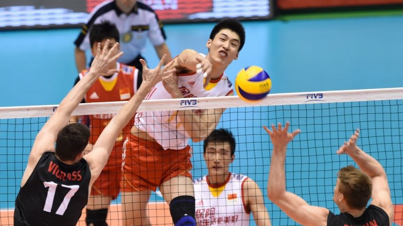 Le joueur chinois Geng Xin (n ° 11) smash la balle sur Graham Vigrass (# 17) et John Perrin (# 2) du Canada lors de la finale du match de qualification masculin de la coupe du monde de volley-ball, pour les Jeux olympiques de Rio de Janeiro 2016. Photo prise à Tokyo le 5 juin 2016 (Toru Yamanaka/AFP/Getty Images)