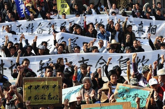 Des villageois portent des bannières durant une manifestation à Wukan, dans la province du Guangdong, le 19 décembre 2011. Ils demandent aux autorités centrales de réagir sur les saisies illégales de terrains et sur la mort d'un dirigeant local en détention. Les promoteurs immobiliers, de pair avec les autorités locales, qui s'approprient les terres et les maisons des citoyens, avec peu ou pas de compensation, sont parmi les personnes les plus méprisées en Chine. (STR/AFP/Getty Images) 