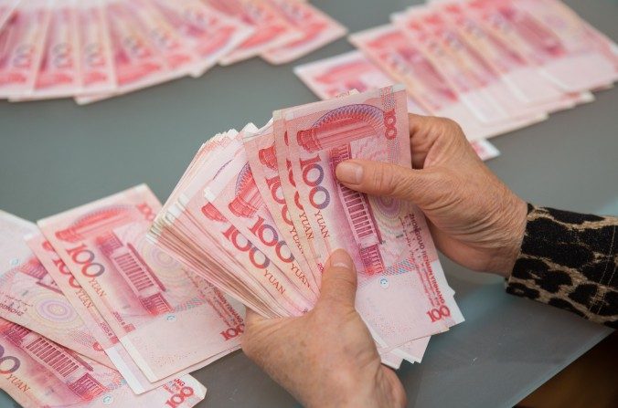 Une femme compte les billets de yuan chinois qui équivalent à des milliers de dollars, à Vancouver, Canada, le 27 octobre 2015. (Benjamin Chasteen / Epoch Times)
