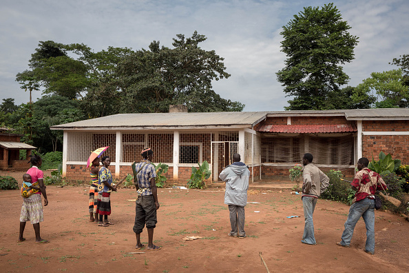 Ancien prêtre de Gambo, l'abbé Junior (manteau gris) visite une paroisse entourée de survivants et de combattants antibalakas, le 16 août 2017 à Gambo, au sud-est de la République centrafricaine. La paroisse a été pillée par des combattants de Seleka lors de l'attaque du 5 août à Gambo.  (ALEXIS HUGUET/AFP/Getty Images)