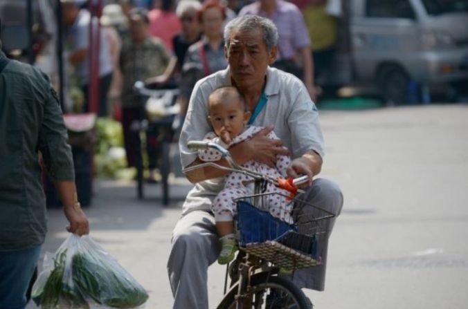 Un homme âgé se déplace à Pékin à vélo avec un bébé, le 8 septembre 2015. ( Wang Zhao / AFP / Getty Images)