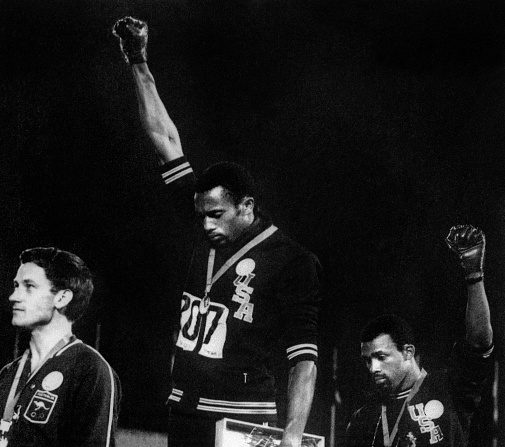 Les athlètes noirs américains Tommie Smith et John Carlos, 1er et 3e du 200 m aux Jeux olympiques de Mexico en 1968, baissent la tête, levant un poing ganté de noir, lors de l’hymne américain, en signe de soutien à la cause des noirs américain. Sur la deuxième marche du podium, Norman, athlète blanc, s'associe à leur geste en arborant le badge d'un mouvement pour les droits civiques, "Olympic project for human rights" (OPHR), qui avait invité les athlètes de couleur à boycotter les JO mexicains. (-/AFP/Getty Images)