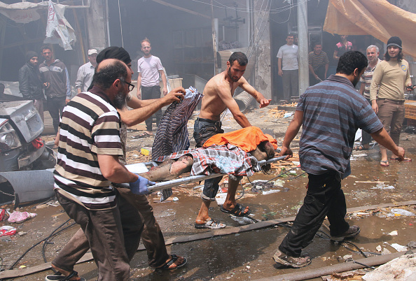 Les hommes syriens portent le corps d'une victime sur un brancard à la suite d'attaques aériennes.  
  MOHAMED AL-BAKOUR / AFP / Getty Images

