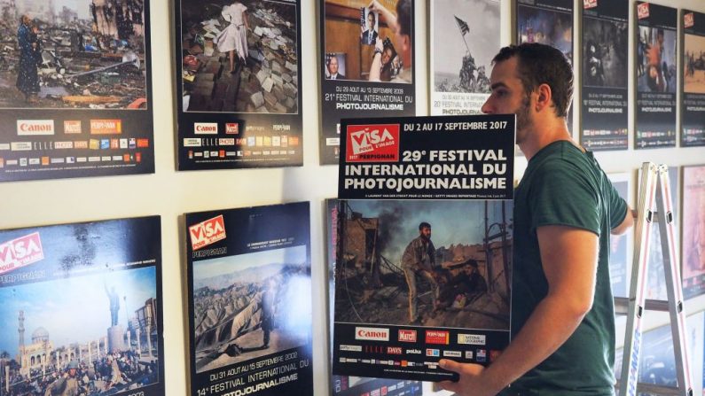 Un homme accroche l'affiche de la 29e édition du festival de photojournalisme de Perpignan  "Visa pour l'image", le 22 août 2017, à Perpignan. (Photo de RAYMOND ROIG/AFP/Getty Images)