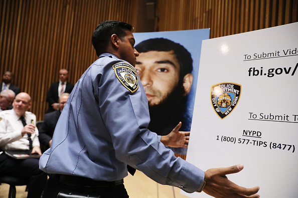 Un policier de New York se tient à côté d'une photo du terroriste Sayfullo Saipov lors d'une conférence de presse sur l'attaque de Manhattan. Huit personnes ont été tuées et 12 autres blessées mardi après-midi lorsque Sayfullo Saipov, âgé de 29 ans, a intentionnellement conduit un camion sur une piste cyclable dans le sud de Manhattan. (Spencer Platt / Getty Images)