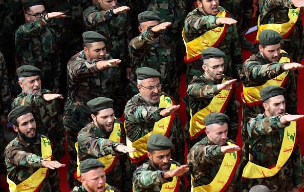 Des membres du mouvement terroriste armé libanais chiite Hezbollah font le salut nazi derrière les cercueils de trois camarades tués au combat en Syrie lors de leurs funérailles dans la ville de Nabatieh, au sud du Liban, le 8 novembre 2017. / AFP PHOTO / Mahmoud ZAYYAT (Crédit photo: MAHMOUD ZAYYAT / AFP / Getty Images)