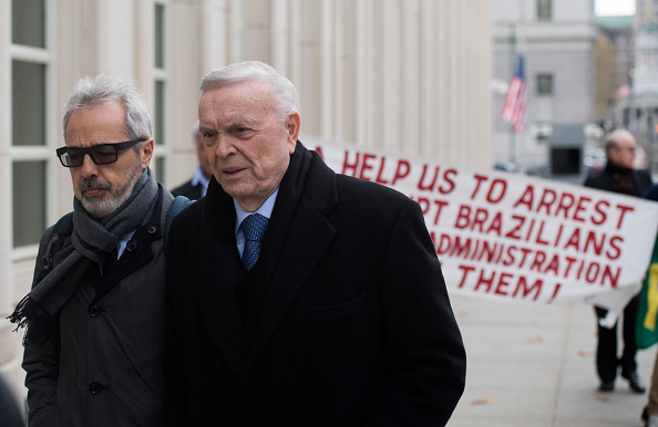 Des manifestants portent une pancarte derrière l'ancien président de la Fédération nationale brésilienne de football, Jose Maria Marin, alors qu'il arrive le 8 novembre 2017 au Brooklyn Federal Courthouse à New York.
(DON EMMERT / AFP / Getty Images)