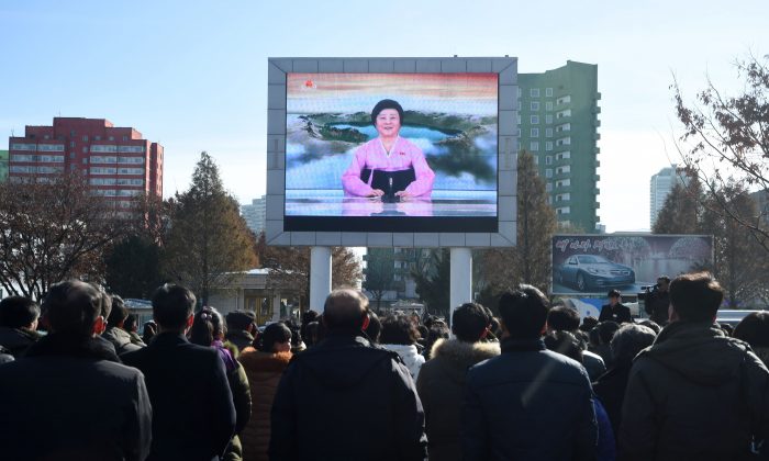 Les habitants de Pyongyang écoutent, sur un grand écran près de la gare ferroviaire, les nouvelles à la télévision officielle annonçant le succès du tir du nouveau missile balistique intercontinental à Pyongyang le 29 novembre 2017. Le leader nord-coréen Kim Jong-un a déclaré, le 29 novembre, que son pays avait atteint le statut d'État nucléaire à part entière après avoir testé avec succès un nouveau missile capable de frapper n'importe où aux États-Unis. (KIM WON-JIN/AFP/Getty Images) 