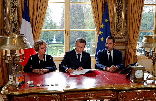 Le président Emmanuel Macron signe des documents devant les médias pour promulguer une nouvelle loi sur le travail dans son bureau de l'Elysée à Paris, le 22 septembre 2017, sous la présidence de la ministre française du Travail, Muriel Penicaud Le ministre des Relations avec le Parlement et le porte-parole du gouvernement, Christophe Castaner.
Le 22 septembre, M. Macron a promulgué des changements radicaux au code du travail complexe de la France, scellant une réforme de signature après quatre mois à la barre. Les mesures, qui ont déclenché des protestations de masse, sont conçues pour donner aux employeurs plus de flexibilité pour négocier les salaires et les conditions de travail avec leurs employés et faciliter le licenciement du personnel.
 (PHILIPPE WOJAZER / AFP / Getty Images)