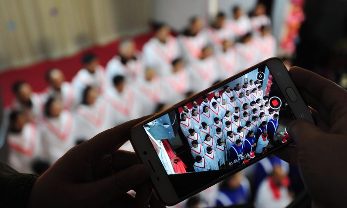 Le chant de chœur est filmé en vidéo par un participant lors de la messe de la veille de Noël dans une église de Fuyang, dans la province orientale d’Anhui, le 24 décembre 2017. Les rapports provenant de toute la Chine témoignent que cette année les célébrations de Noël par les chrétiens chinois ont été largement réprimées par les autorités. (AFP / Getty Images)