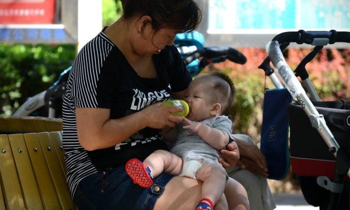 Une femme nourrit son bébé au biberon dans un quartier résidentiel de Pékin, le 8 août 2013. (Wang Zhao / AFP / Getty Images)