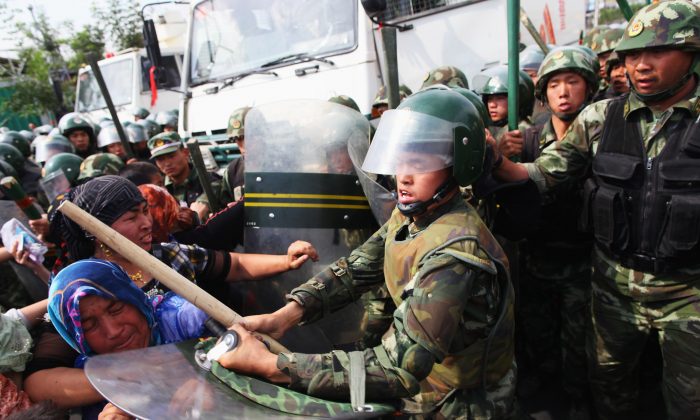 Des policiers chinois poussant des femmes Ouïghoures manifestant dans les rues de Urumqi, la capitale du Xinjiang, Chine, en juillet 2009. (Guang Niu/Getty Images)