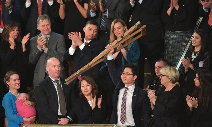 Le dissident nord-coréen Ji Seong-ho lève ses béquilles alors que le président Donald Trump lui rend hommage lors du discours sur l'état de l'Union au Capitole américain à Washington, DC, le 30 janvier 2018. (MANDEL NGAN/AFP/Getty Images)