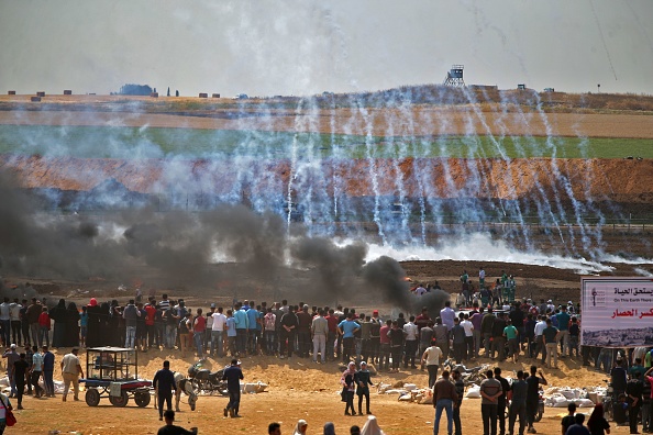 Les manifestants palestiniens envoient des gaz lacrymogènes et de la fumée s'échapper de leurs pneus brûlés à l'est de la ville de Gaza le 14 mai 2018, alors que les Palestiniens s'apprêtaient à protester contre l'inauguration de l'ambassade américaine à Jérusalem. Photo MOHAMMED ABED / AFP / Getty Images