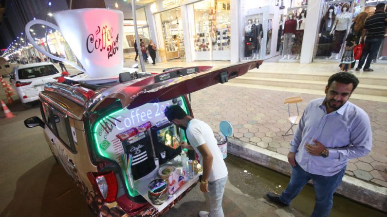 L'Irakien Karrar Alaa (à gauche), âgé de 26 ans, vend son café dans une rue de Bassorah le 17 juin 2018. D'un café itinérant à des sculptures en ferraille, les jeunes irakiens incapables de puiser dans les richesses pétrolières du pays, ont trouvé des façons créatives de gagner leur vie. Photo HAIDAR MOHAMMED ALI / AFP / Getty Images.