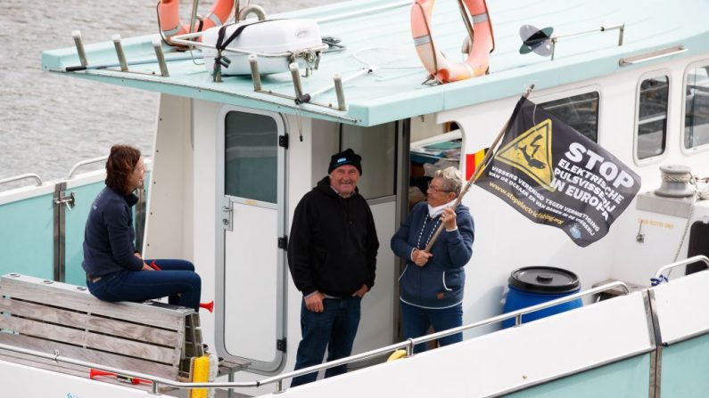 
Une femme sur un bateau tient un drapeau contre l'utilisation de l'électricité dans la pêche commerciale le 18 juin 2018 au port de Nieuport lors d'une manifestation de pêcheurs français.   Photo KURT DESPLENTER / AFP / Getty Images.