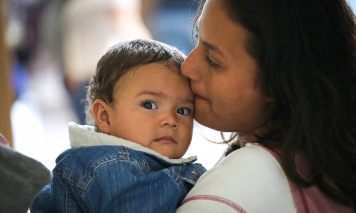 Une mère immigrante et son enfant du Honduras attendent de prendre le bus pour la Floride depuis McAllen, Texas, le 19 août. Après avoir traversé la frontière, les familles reçoivent des documents légaux temporaires de la U.S. Border Patrol, puis sont envoyées dans leur ville de destination, où elles font une demande d'asile politique.  (John Moore/Getty Images)