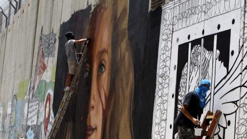 L'artiste italien Jorit Agoch fait une peinture murale représentant l'adolescente palestinienne emprisonnée Ahed Tamimi à côté d'un autre artiste sur la barrière de séparation controversée d'Israël dans la ville de Bethléem en Cisjordanie, le 25 juillet 2018. Photo MUSA AL SHAER / AFP / Getty Images.