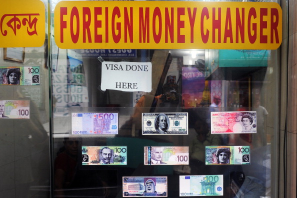 Des exemples de plusieurs billets internationaux sont observés à l'entrée d'une bourse de change à Calcutta. Photo DIBYANGSHU SARKAR / AFP / Getty Images.