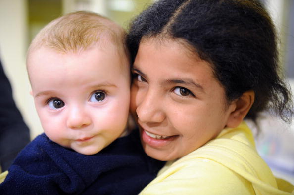 Une fillette de 11 ans originaire du Yémen, pose avec un bébé à Paris. Ali a été mariée à un homme de 30 ans elle a subi des mois d'abus sexuels, mais a réussi à racheter sa liberté par le divorce. Photo BORIS HORVAT/AFP/Getty .Images.