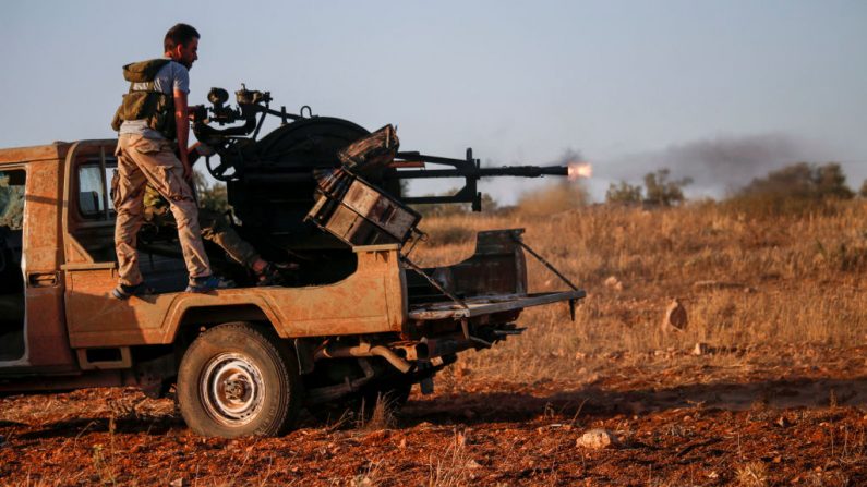 Le 3 juillet 2018. Des rebelles syriens montent à l'arrière d'une camionnette, l'un d'entre eux tire un fusil antiaérien chargé dans le dos près des forces gouvernementales situés à l'ouest de la ville de Daraa, au sud du pays. Photo MOHAMAD ABAZEED / AFP / Getty Images.