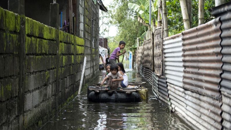 Des enfants utilisent un radeau pour traverser une allée inondée à la suite du Super Typhon Mangkhut à Calumpit, le 16 septembre 2018. Photo NOEL CELIS / AFP / Getty Images.