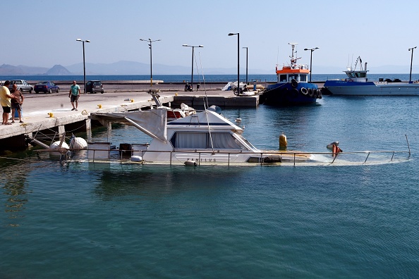 -Les gens regardent un bateau partiellement submergé dans le port de l'île de Kos, à la suite d'un séisme de magnitude 6,5 qui avait frappé la région. Photo d’illustration LOUISA GOULIAMAKI / AFP / Getty Images.