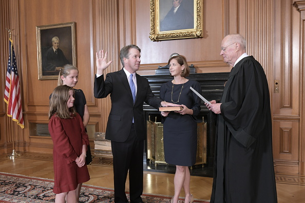 Une photo fournie par la Cour suprême des États-Unis, le juge Anthony M. Kennedy (retraité) administre le serment judiciaire au juge Brett M. Kavanaugh alors que son épouse Ashley Kavanaugh tient la Bible, accompagnés par leurs filles Margaret et Liza, dans la salle de conférence des juges au Palais de la Cour suprême le 6 octobre 2018 à Washington, DC. Photo de Fred Schilling / Cour suprême des États-Unis via Getty Images.