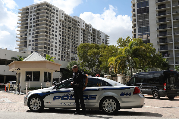 -Un agent de police d’Aventura City se tient en face du bâtiment qui pourrait avoir des liens avec le présumé kamikaze Cesar Sayoc et sa mère le 26 octobre 2018 à Aventura en Floride. M. Sayoc a été arrêté aujourd'hui, accusé d'avoir envoyé par la poste des bombes artisanales visant les détracteurs du président Donald Trump. Photo par Joe Raedle / Getty Images.