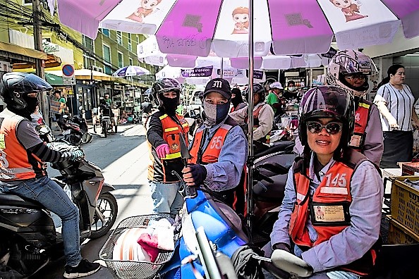 -Cette photo prise le 26 septembre 2018 montre trois chauffeuses de taxi-moto en attente à un stand de taxi-moto à Bangkok. Photo LILLIAN SUWANRUMPHA / AFP / Getty Images.