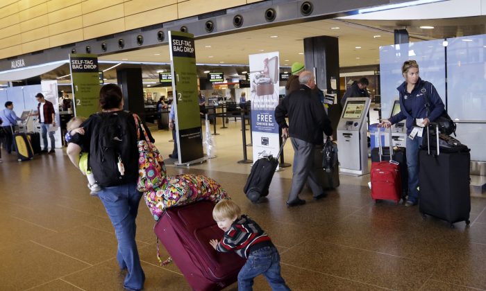 Colin Drummond, 4 ans, pousse ses bagages par derrière alors qu'il marche avec des membres de sa famille pour enregistrer un parent à un vol d'Alaska Airlines, à l'aéroport international Seattle-Tacoma de SeaTac (Washington), le 24 mars 2015. (Elaine Thompson/AP Photo)