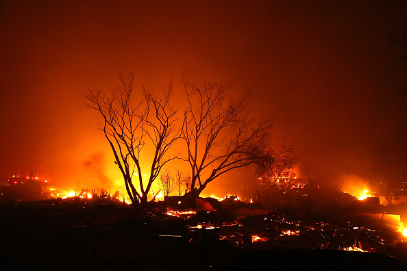 -Un feu  consume des maisons et des entreprises le 8 novembre 2018 à Paradise, en Californie. Alimenté par des vents violents et un faible taux d’humidité, le feu s’est rapidement répandu a ravagé la ville de Paradise. Photo par Justin Sullivan / Getty Images.