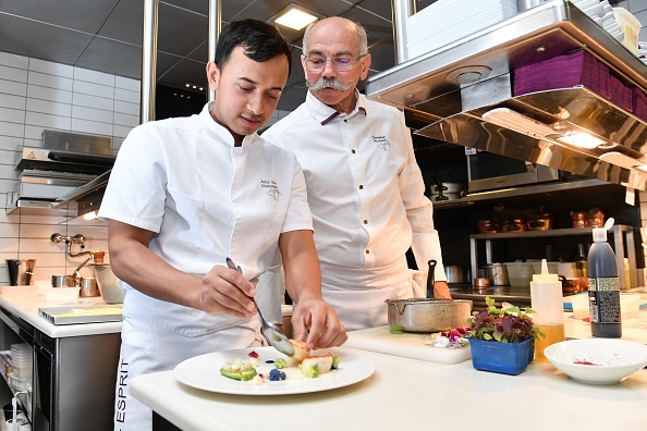 -L'apprenti chef bangladais Ariful Islam Mozumder prépare un plat avec son maître, le chef étoilé Christian Morisset, dans la cuisine du restaurant Le Figuier Saint Esprit le 24 octobre 2018 à Antibes, dans le sud-est de la France. il a remporté le trophée d'or l'un des meilleurs apprentis cuisiniers de France. Photo YANN COATSALIOU / AFP / Getty Images.