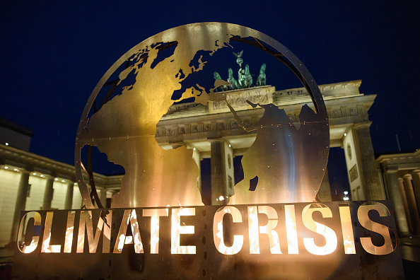 -L'emblème de Berlin, la porte de Brandebourg, est visible à travers une installation de globe géant érigée le 11 décembre 2018 par les environnementalistes de Greenpeace. La COP24 qui se déroulent actuellement dans la ville minière polonaise de Katowice. Photo de GREGOR FISCHER / AFP / Getty Images.