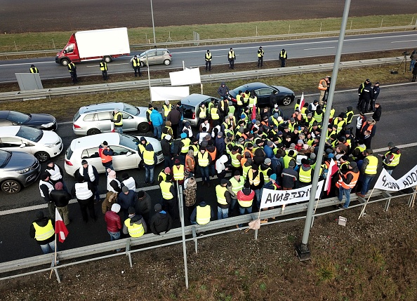 -Des agriculteurs polonais, vêtus de gilets jaunes comme les manifestants français, bloquent l'autoroute A2 en direction de Varsovie le 12 décembre 2018, lors d'une manifestation pour demander au gouvernement d'apporter un soutien efficace aux agriculteurs touchés par la dernière épidémie de peste porcine africaine. Photo MATEUSZ GROCHOCKI / AFP / Getty Images.