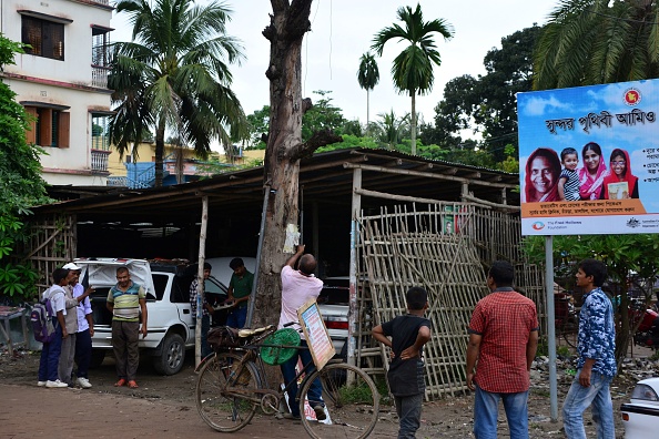 -Sur cette photo prise le 13 octobre 2018, l'écologiste environnementaliste du Bangladesh, Ohid Sarder, enlève des clous d'un tronc d'arbre près d'une route à Jessore, un district de l'ouest du Bangladesh. – Cet amoureux des arbres âgé de 53 ans, parcourt le pays à vélo, son effort vise à libérer les arbres des panneaux d’affichage, des clous qui encombre leur tronc. Photo REDWAN AHMED / AFP / Getty Images.