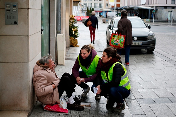 -Ludivine Hilairet une jeune de 21 ans, travaillant dans un fast-food et Chloé Tessier, surveillante équestre au chômage âgée de 28 ans, portent le 'Gilet jaune', en conversation avec un homme assis dans une rue de Caen, Nord-Ouest de la France, le 21 décembre 2018. Le mouvement « Gilets jaunes » en France a commencé comme une manifestation contre des hausses de prix du carburant, mais il s'est transformé en une manifestation de masse contre la politique présidentielle et l’incompréhension des politiques à la vie des gens. Photo CHARLY TRIBALLEAU / AFP / Getty Images.